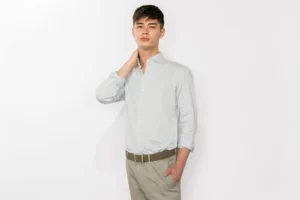 A man wears a light shirt, beige chinos and a brown belt for a spring look